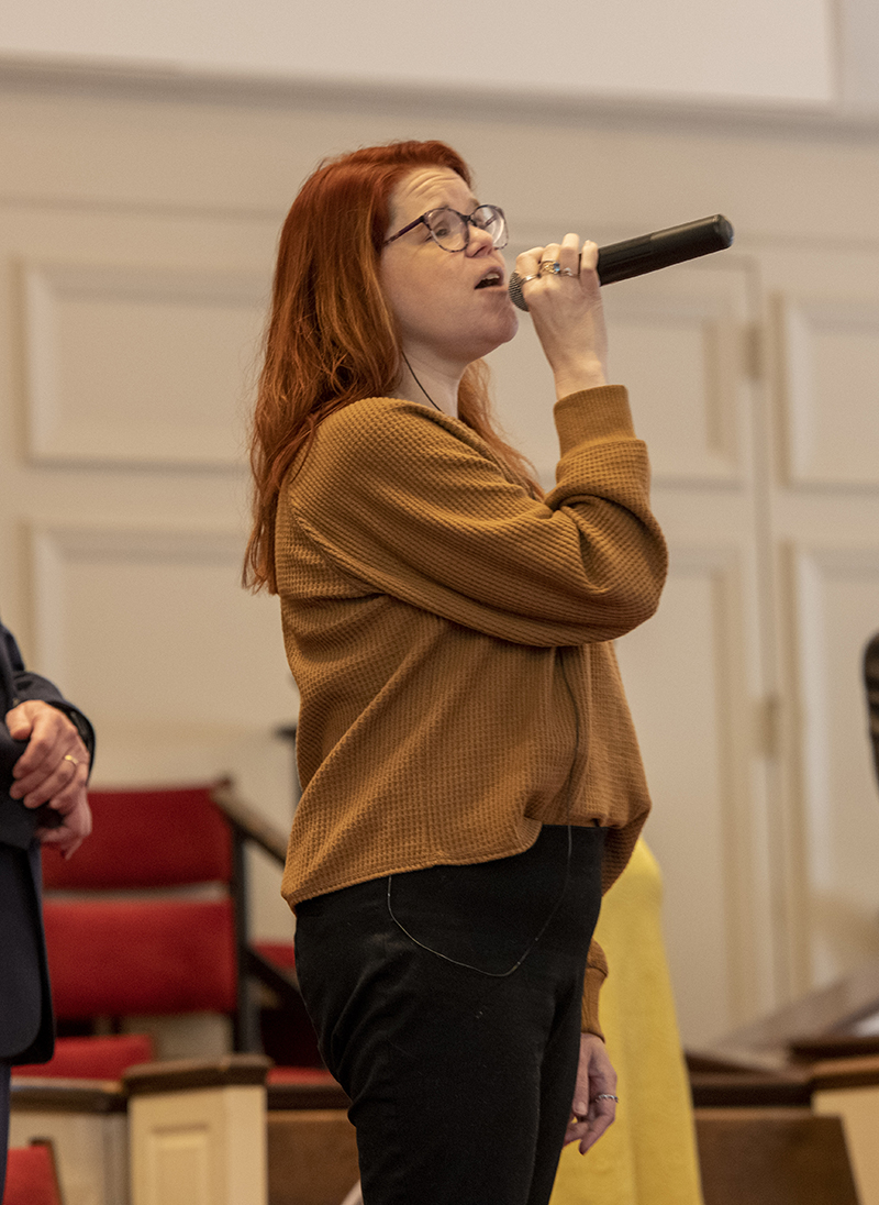 A female sings into a microphone during the service at HRBC.