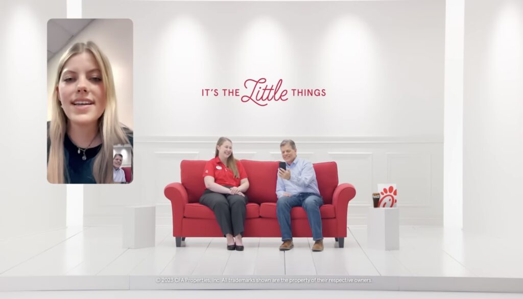 Bob Lee on the Chick-Fil-A red couch with his daughter Isabella showing in a corner window