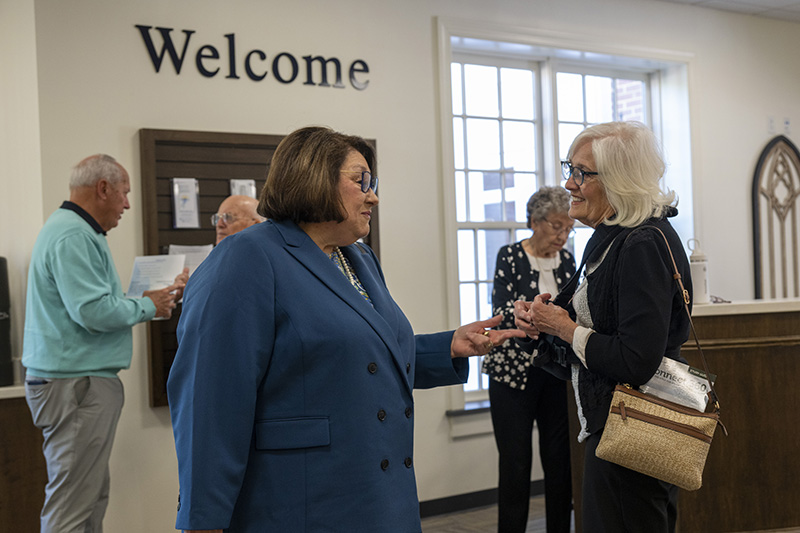 Welcome! Two ladies talk near a Welcome sign at Huguenot Road Baptist Church